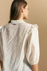 Camisa de manga corta abullonada con terminación elastizada, cuello con leve frunce y calce recto. Presenta una estampa floral integral sobre fondo claro.