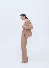 Pantalón de vestir color beige, de corte recto, con bolsillos laterales y traseros. Se ajusta a la cintura con botón y cierre.