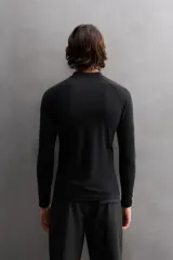 Camiseta de surf compresiva slim fit confeccionada en tejido técnico muy elástico y ligero. Con factor de protección ultravioleta 40+, cuello subido, manga larga, costuras planas y acabados combinados a contraste.