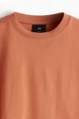 Remera color salmón de corte holgado, cuello redondo y mangas cortas.