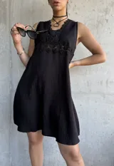 Vestido corto negro con escote en V, breteles finos y detalle de encaje en el busto.