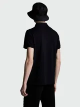 Polo de piqué de algodón color negro, con cuello clásico, tapeta de botones y logo de la marca bordado en el pecho.
