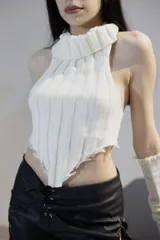 Top blanco de tejido de punto con cuello alto, corte irregular y terminaciones desflecadas.