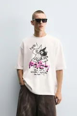 Camiseta blanca de corte holgado, con cuello redondo y mangas cortas. Estampado en el frente con dibujos de gatos, texto en japonés y frases en inglés.