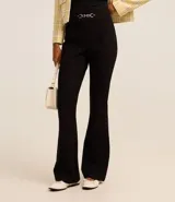 Pantalón flare de punto roma color beige, con detalle metálico en la cintura y cierre frontal.