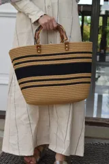 Bolso de tejido en tonos marrón y negro, con asas de madera y diseño estilo tote.