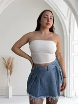 Short pollera de jean celeste con diseño asimétrico, tablas y detalle de cintas laterales.