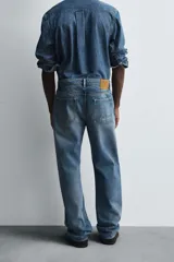 Pantalón de jean celeste de corte recto, con cinco bolsillos y cierre frontal con botones.