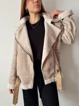 Campera color beige con interior de corderito blanco, cierre cruzado con cremallera y cinturón con hebilla.