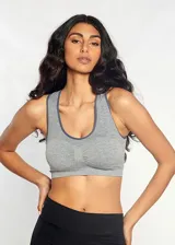 Top deportivo gris con espalda cruzada, breteles anchos y copas forradas con relleno extraíble. Sujeción suave para ejercicio de bajo impacto. Modelo diseñado con el mínimo de costuras para un ajuste más cómodo.