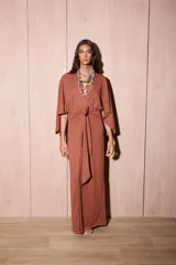 Vestido largo tipo kimono de color marrón, confeccionado en tela de punto texturada. Posee mangas amplias y abiertas, escote en V pronunciado y un lazo ajustable en la cintura para definir la silueta.