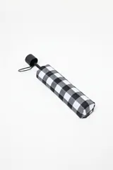Paraguas plegable con funda textil estampada con patrón de cuadros vichy en blanco y negro. Presenta un mango y detalles en plástico negro.