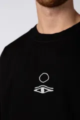 Remera color crudo de corte oversize con estampado pequeño en el centro del pecho.