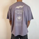 Remera lila con estampado en la espalda que incluye texto, un logo y un diseño geométrico.