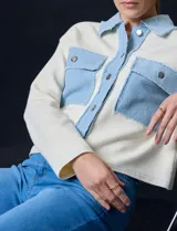 Campera combinada de punto color crema con detalles en denim celeste. Tiene cuello con solapa, cierre frontal con botones metálicos, bolsillos delanteros y corte recto.