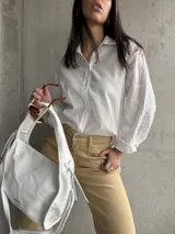 Camisa blanca de manga larga con bordado floral en las mangas.