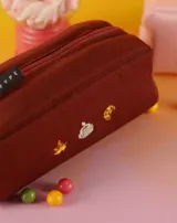 Neceser naranja de tela con cierre superior y logo de la marca en etiqueta negra. Presenta bordados de emojis: copa de vino, fuegos artificiales y mano verde.