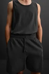 Bermuda jogger negra confeccionada en tejido de algodón con interior de rizo, cintura elástica ajustable con cordón y bolsillos laterales.