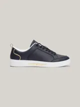 Zapatillas Tommy Hilfiger de cuero azul marino con suela blanca, cordones negros, interior blanco y detalles dorados en el talón y en el lateral.