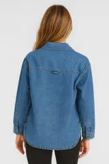 Sobrecamisa azul de jean con corte holgado, cuello camisero, cierre con botones a presión y dos bolsillos de parche en el pecho.