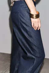 Pantalón de jean azul oscuro, de tiro alto, corte ancho y largo hasta el tobillo.