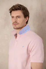 Chomba azul con cuello clásico, tapeta de dos botones y logo bordado en el pecho.