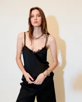 Top negro estilo lencero con escote en V, puntilla de encaje y breteles finos. La espalda es baja con un recorte de gasa que genera transparencia.