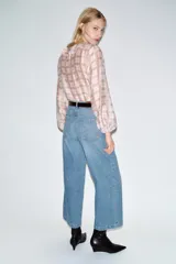 Jeans de tiro alto con pernera ancha y corte cropped. Presenta diseño de cinco bolsillos, cierre frontal con cremallera y botón, e incluye un cinturón a juego.