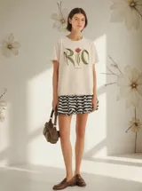 Remera color crema con estampado de la palabra "RIO" con forma de hojas y una flor roja.