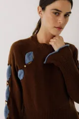 Sweater color gris claro con cuello redondo, mangas largas acampanadas y aberturas circulares en hombros y mangas con detalles de tela blanca.