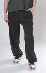 Pantalón negro de corte holgado con bolsillos laterales y cintura elástica ajustable con botón y cierre.