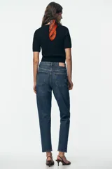 Pantalón de jean negro de corte recto, tiro alto y largo tobillero.