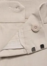 Pantalón de vestir color beige, de tiro alto, corte recto y largo. Presenta cierre frontal con botón, gancho y cremallera oculta, trabillas, bolsillos laterales, pinzas delanteras, forro interior y bolsillo de ribete en la parte posterior.