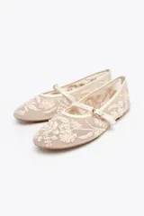 Zapato plano tipo bailarina color beige, con cuerpo de mesh bordado con flores y perlas, tira delantera con hebilla y punta redonda.