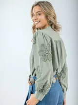 Camisa color crema de broderie, corte holgado, con cuello mao y mangas largas abullonadas con bordados florales.