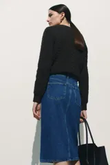 Pollera midi de jean azul, de cinco bolsillos, con tajo frontal y cierre con botón.