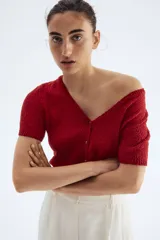 Cárdigan rojo de tejido slub con cuello en V, manga corta y cierre frontal con botones.