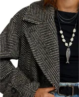 Abrigo tipo peacoat de corte oversize y silueta cuadrada, confeccionado en mezcla de lana con patrón de espiga en tonos negro y gris. Presenta cuello de solapa, cierre frontal de doble botonadura y mangas largas.