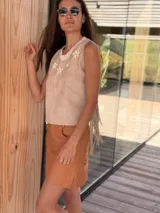 Top color beige de cuero con flecos en los laterales y caracoles buzios en el frente. Espalda tejida.