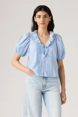 Blusa celeste con estampado floral, cuello en V con volantes, mangas cortas abullonadas y cierre frontal con botones.