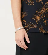 Pulsera de eslabones gruesos color plateado, con placa rectangular lisa para grabar.