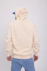 Canguro color crema con capucha y cordones ajustables. Estampado en relieve con la palabra "ORIGINAL" y el logo de la marca Jack & Jones.