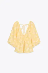 Top amarillo con estampado floral en jacquard, escote en pico, mangas cortas abullonadas con elástico, cintura elástica y espalda descubierta ajustable con lazos.