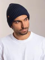 Gorro de lana azul marino con textura acanalada y etiqueta de cuero con logo de la marca en el lateral.