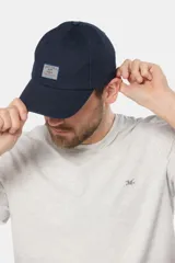 Gorra de béisbol azul marino confeccionada en lona de algodón, con visera curva y parche rectangular con logo en el frente.