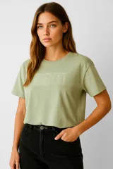 Remera verde con estampado de sellos postales en el frente, de manga corta y cuello redondo.