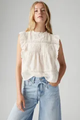 Blusa blanca sin mangas con cuello alto y detalles de encaje y volados.