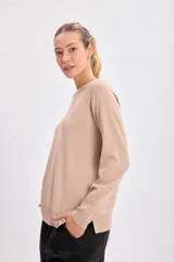 Buzo básico de tejido de punto color beige, con cuello redondo y mangas largas.