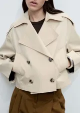 Chaqueta corta color beige con doble botonadura, cuello con solapa y bolsillos laterales.