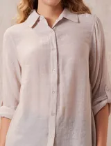 Camisa color beige claro, de corte recto y mangas 3/4 con botón para sujetar.